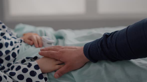 Closeup of Sick Child Resting in Bed with Oximeter on Finger Monitoring Heartbeat Pulse