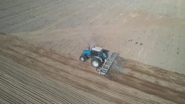 Aerial top view of a tractor, combine harvester plowing agricultural land in the spring