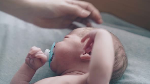 Loving Mother Hand Caresses and Pets Adorable Newborn Boy