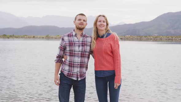 Caucasian couple having a good time on a trip to the mountains, embracing and raising their hands