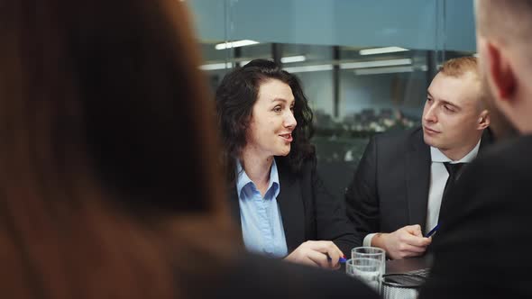 Female top manager talking to colleagues at business meeting