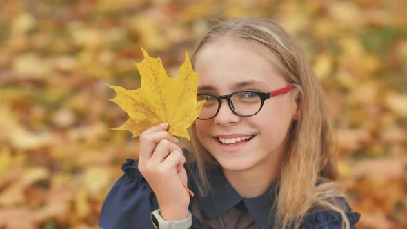 A Young Girl of 13 Years Old with Autumn Leaves Poses in Front of a Video Camera