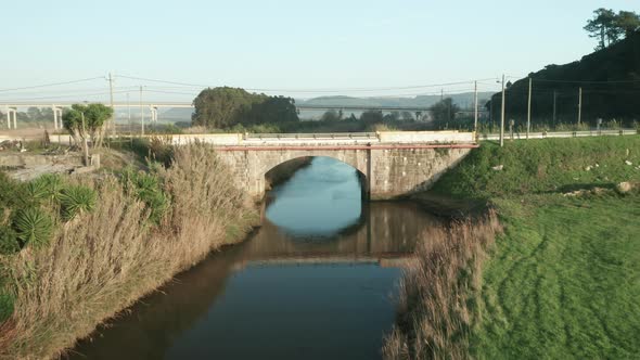 Flying Towards Old Stone Arch Bridge Over Tranquil Lake Of Alcobaca River Near Nazare, Portugal. - D