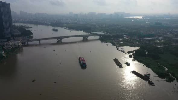 Early morning high drone view looking down on river modern traffic bridge and boats transporting shi