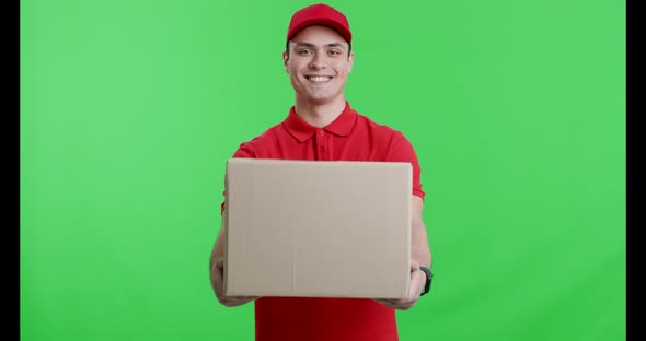 Friendly Courier in Red Uniform Offering Big Parcel To Camera