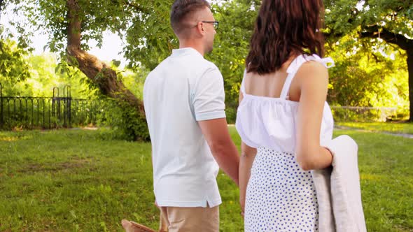 Happy Couple with Picnic Basket at Summer Park