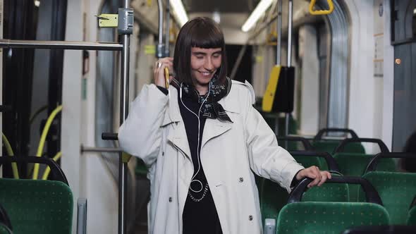 Portrait of Young Woman Wearing in Coat with Headphones Listening To Music and Funny Dancing in