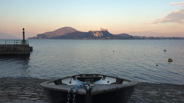 Establishing static shot of fishing boat pulled out of water of Lake Maggiore at sunset, Italy