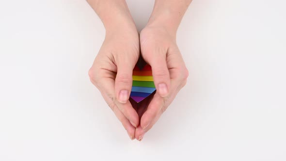 A Woman Opens Her Palms and Shows a Rainbow Heart on a White Background