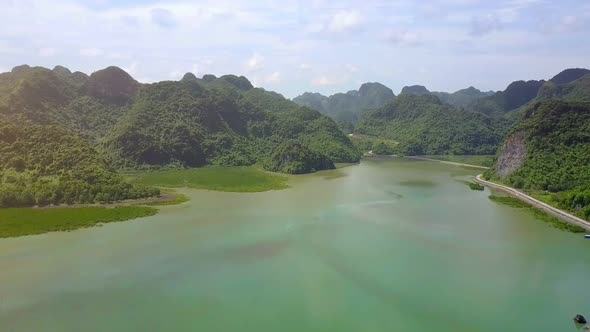 Drone Shows Long Road Around Island Against Pictorial Sea Bay