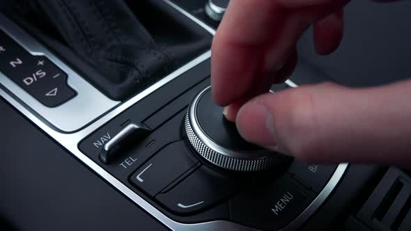 A Man Turns and Presses a Knob on the Gearshift Box of a Luxurious Car - Closeup