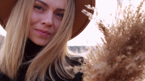 Millennial Woman European Blonde Woman Smiling with Beige Hat in Black Sweater in the Countryside