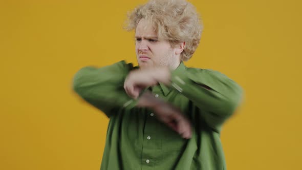 Portrait of Offended Young Man Crossing Arms and Showing Tongue on Yellow Background