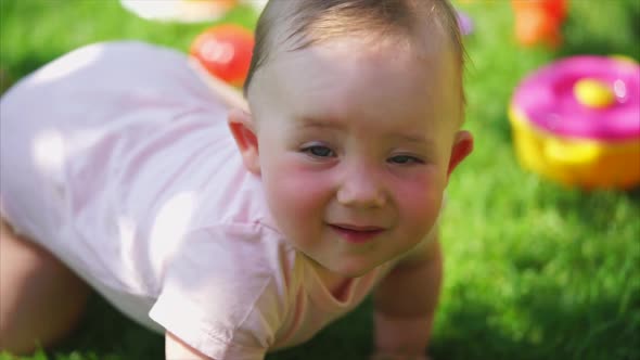 Funny and Cute Baby Crawls on Legs and Hands on Green Grass in Summer