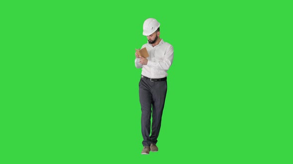 Confident Mature Man in Formalwear and Hardhat Writing Down Notes on a Green Screen, Chroma Key.