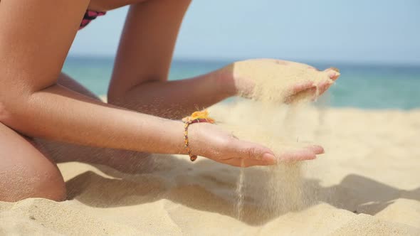 Young Lady Plays with Pouring Sand Resting on Ocean Beach