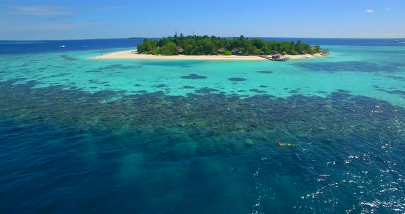 Aerial drone view of a man and woman couple snorkeling over a coral reef of a tropical island