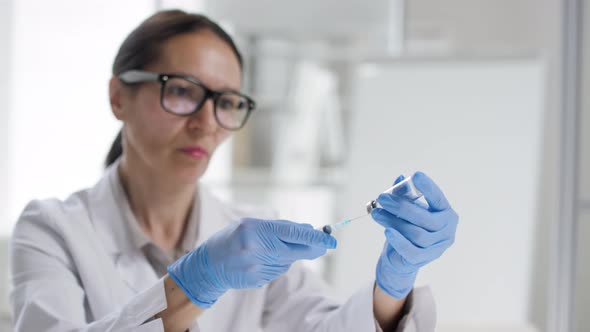 Female Doctor Filling Syringe with Medicine from Vial