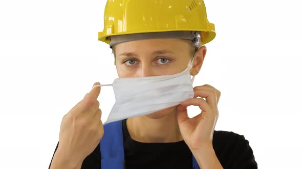 Female Construction Worker in Safety Helmet Putting Medical Mask on on White Background