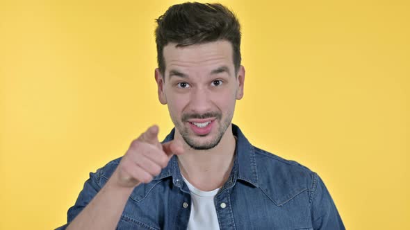 Portrait of Attractive Young Man Pointing at Camera, Yellow Background