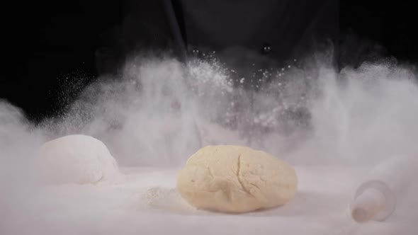 Cloud of White Flour Caused By Chef in Dark Suit Slamming Glob of Dough Onto the Table