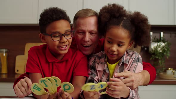 Cheerful Granddad and Smart African American Grandchildren Learning ABC Indoors