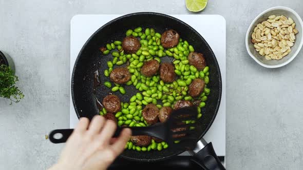 Woman cooking green beans and meatballs