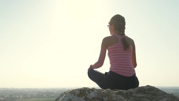 Young Relaxed Woman Sitting Outdoors on a Big Stone Enjoying Warm Summer Day