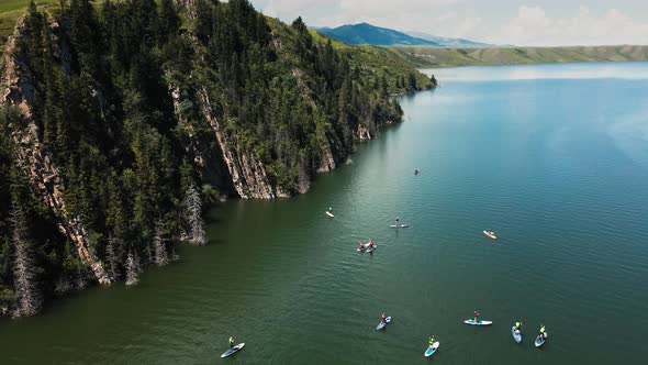 People Ride on SUP Board in the Mountain Lake