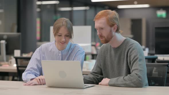 Young Man and Woman Discussing Work on Laptop