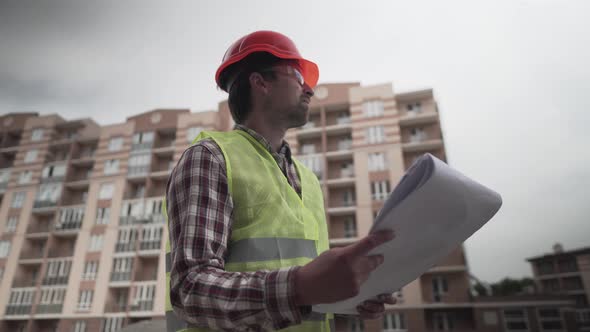 Construction Inspector with Blueprints on Building Site