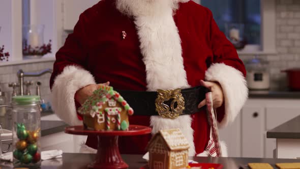 Santa Claus in kitchen putting on apron alt