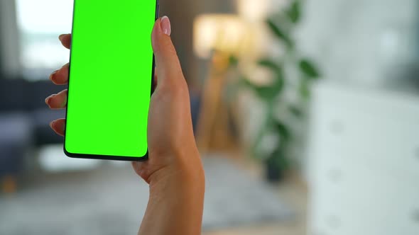 Woman at Home Using Smartphone with Green Mockup Screen in Vertical Mode