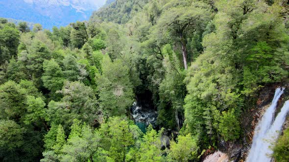 Tilt up aerial view of the Rio Blanco waterfall and forest in Hornopiren National Park, Chile. Snow-