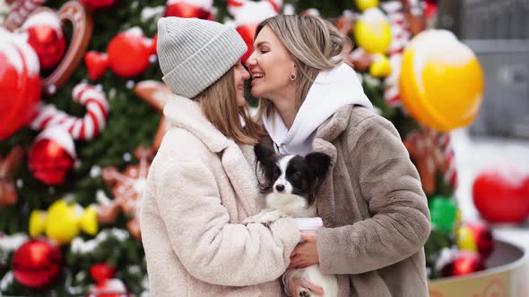 Mom and Daughter with Dog Papillon Near Christmas Tree on Street