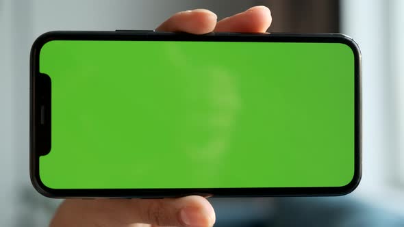 Close-Up Of A Woman's Hand Holding Horizontally a Smartphone with a Green Screen