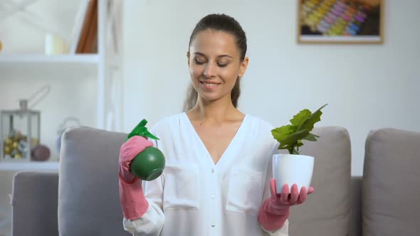 Smiling Woman Holding Water Sprayer and Flowerpot, Looking at Camera, Home