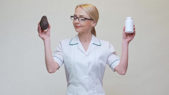 Nutritionist Doctor Holding Organic Avocado Fruit and Jar of Medicine or Vitamin or Omega 3 Capsules