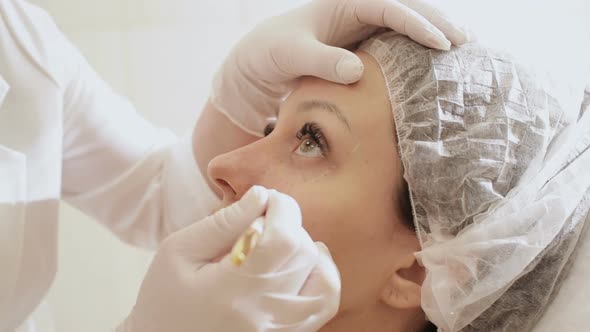 Closeup Beautician Draws the Contours of a White Pencil on the Face of the Patient