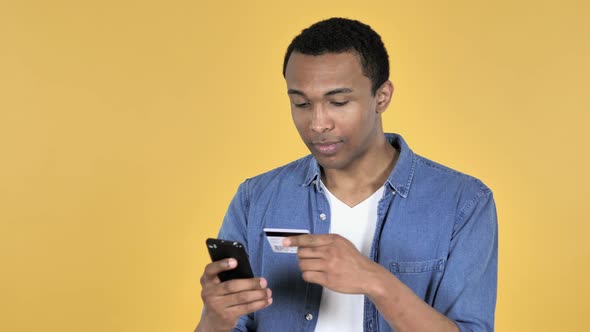 Online Shopping on Smartphone By Young African Man, Yellow Background