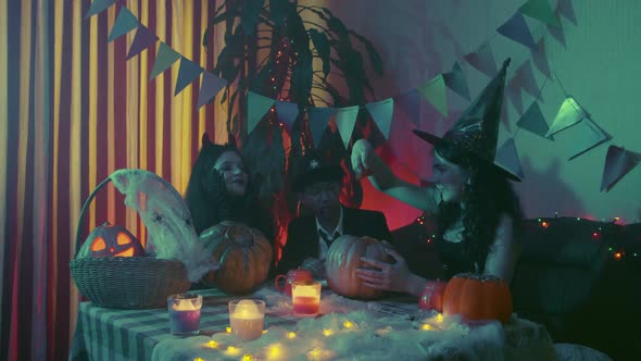 Two Girls and a Guy in Creepy Halloween Costumes are Sitting at a Table and Taking the Pulp Out of