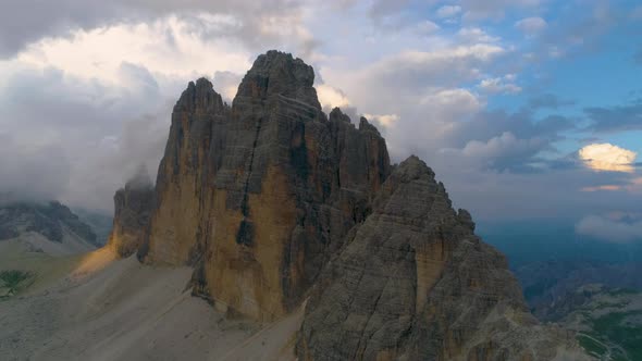 Aerial view orbiting Tre Cime mountain range rock formation peaks against blue sky mountain landscap