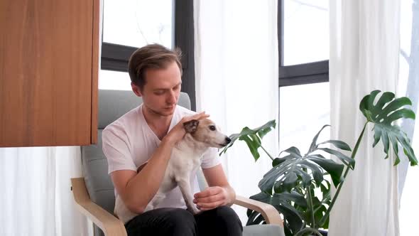 Smiling Man Stroking Purebred Dog in Armchair