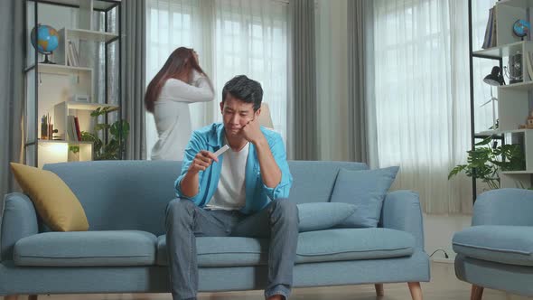 Worried Man Is Holding Pregnant Test Stick While Nervous Woman Walking On Background