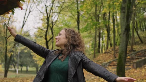 Attractive Woman Having Fun with Umbrella From Leaves in Autumn Park