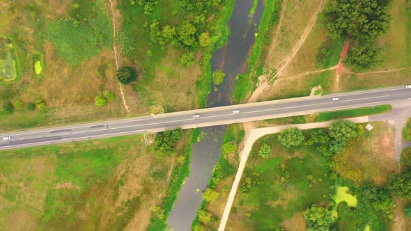 aerial drone shoot. Flying over a bridge green field in a rural landscape. Top view of trees in fore