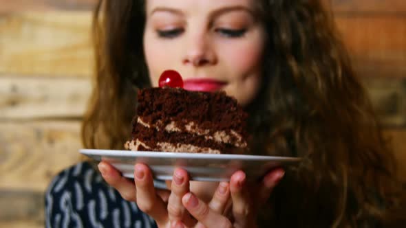 Portrait of female customer holding plate with pastry