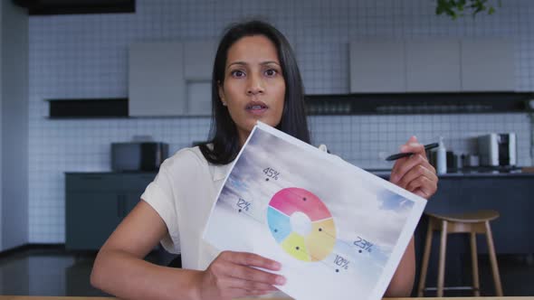 Mixed race businesswoman having video chat going through paperwork in office kitchen