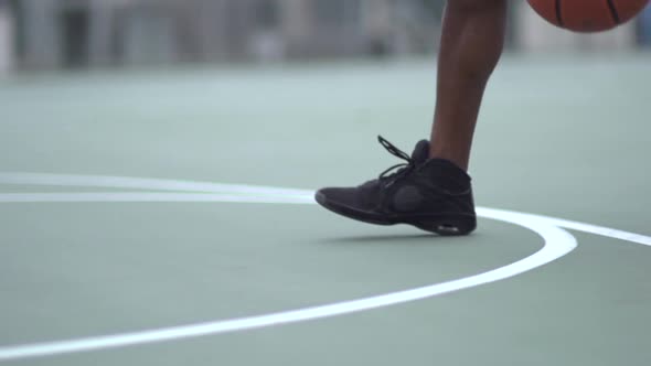 A young man playing basketball on a rainy day.