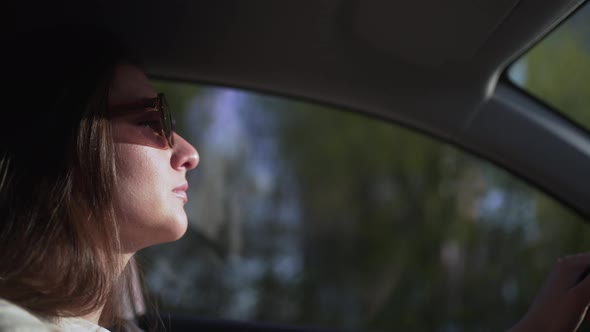 Young Woman Taxi Driver with Glasses Riding at Sunset Side View